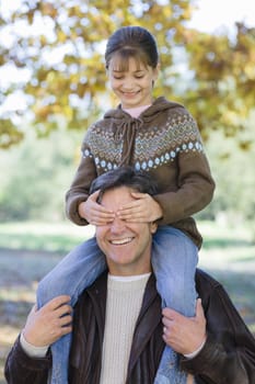 Portrait of a Father Holding Daughter on His Shoulders in a Park