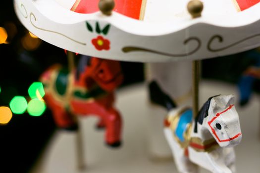 Miniature carousel with horses, against the background of New Year's lights. Depth of field for strong emotions.