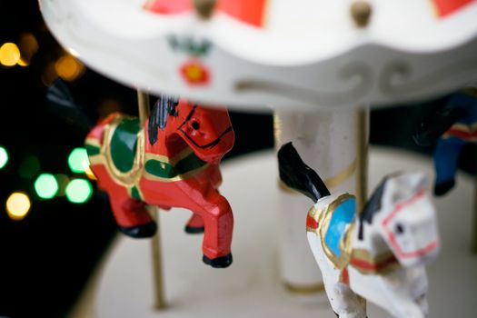 Miniature carousel with horses, against the background of New Year's lights. Depth of field for strong emotions.