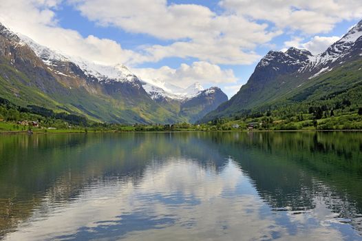 Quiet norway lake surrounding by snow-covered mountains