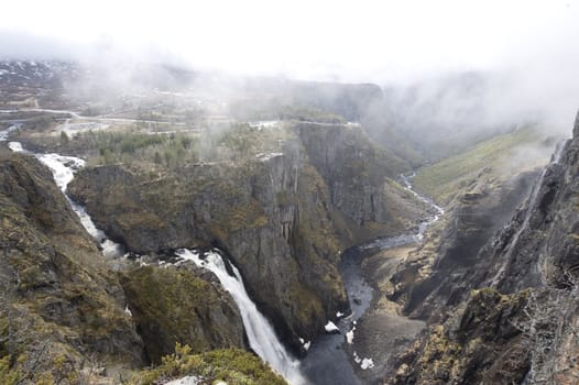 Smoke above river in Norway canyon. Frozen mountain river