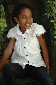 little asian girl sit down beside the tree in park
