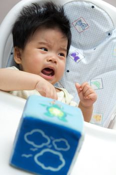Little Asian baby girl crying on a high chair