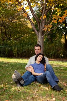 A couple relaxing in the park by a tree