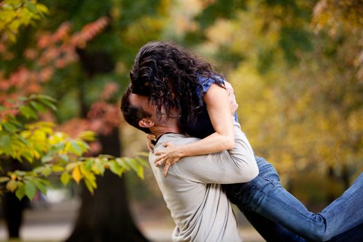 A man giving a woman a big hug in a park