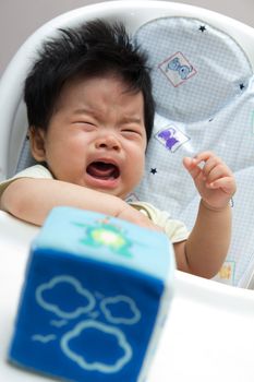 Little Asian baby girl crying on a high chair