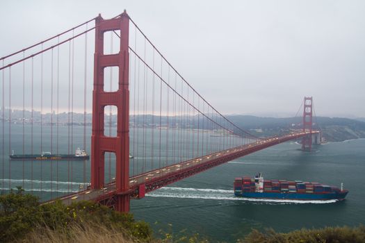 Container cargo ship passing underneath Golden Gate bridge