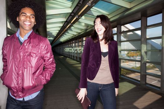 Two young people walking and joking in an urban setting - sharp focus on male