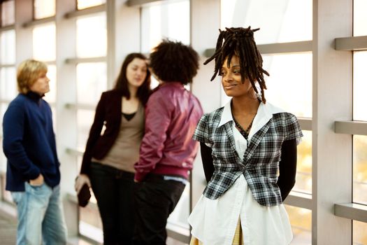 A portrait of an African American woman with dreadlocks with friends in the background