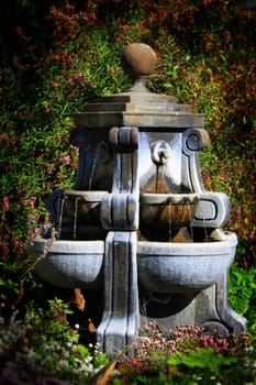 Water fountain with a green garden in the background.