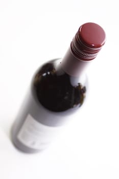 A bottle of red wine looking from above creating a foreshortened perspective and soft focus. Set on an isolated white background.