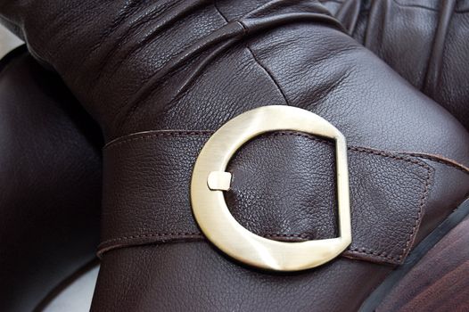 Golden buckle of leather brown boot over white