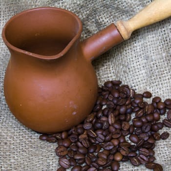 Ceramic Coffee Pot and Coffee Beans on Linen Background