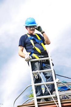 Construction worker standing on roof near ladder