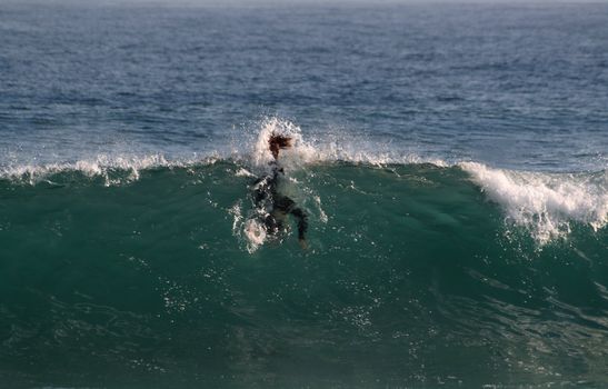 A wave hitting the face of a young surfer funny situation.
