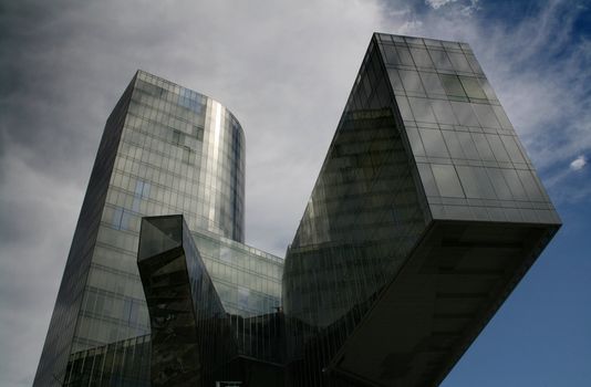 Business building, blue glass, clouded sky background
