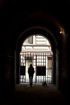 Girls with dog goes on street through archway