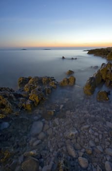 Rocks in the sea after sunset with blurry water