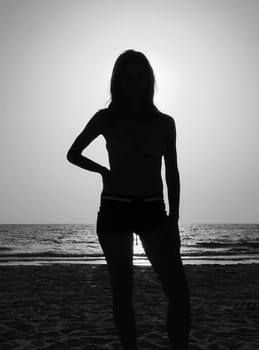 Silhouette of athletic woman watching glistening waves of the ocean