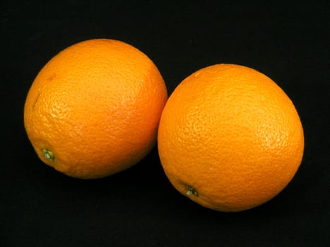 Two navel oranges against a black background.