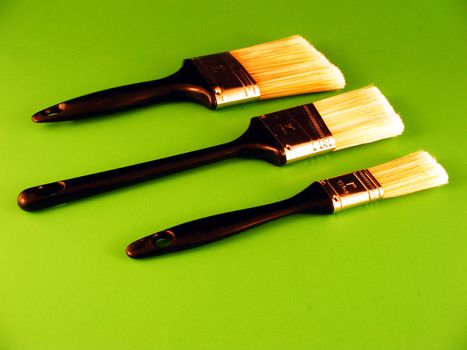 Three paintbrushes against a green background.