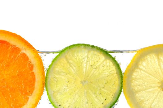 Orange lemon and lime slices in water with air bubbles on white background