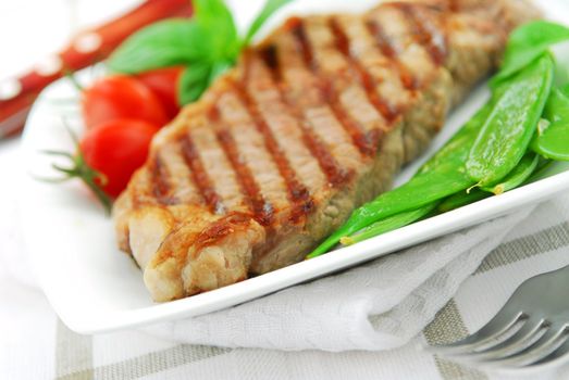 Grilled New York beef steak served on a plate with vegetables