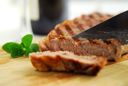 Grilled steak being cut on a cutting board