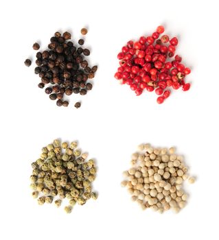 Heaps of assorted peppercorns on white background, top view