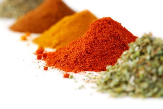 Heaps of various ground spices on white background