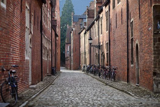 Bicycle leaned to a wall of brick medieval house; cobblestone pavement