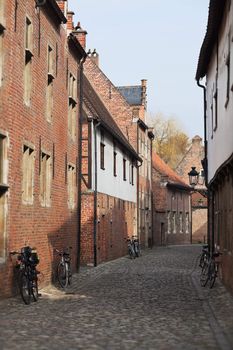 Bicycle leaned to a wall of brick medieval house; cobblestone pavement