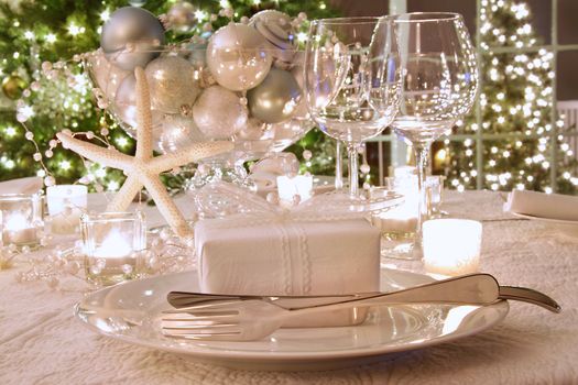 Elegantly lit  holiday dinner table with wine glasses and white ribbon gift
