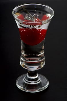 Tomato in a wine-glass. A black background. Studio shooting