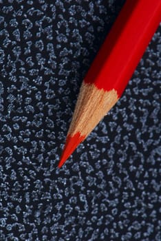 Red pencil on a notebook from an artificial leather. A close up