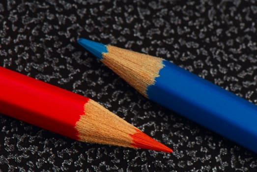 Red and blue pencils on surface from  artificial leather. A close up