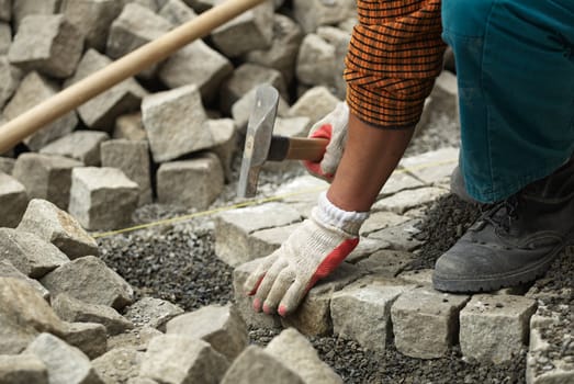 Male hand with brick hammer repairing the pavement