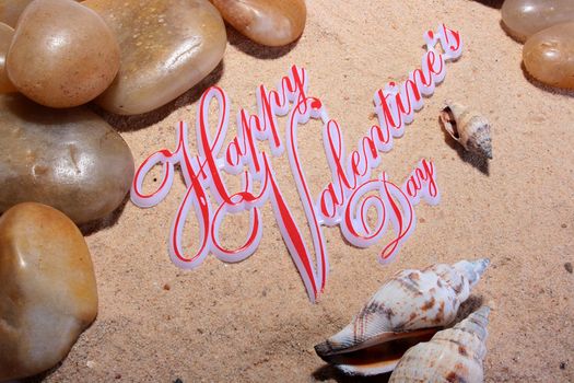 Sea sand with cockleshells and stones, on sand inscription Happy Valentine's Day.
