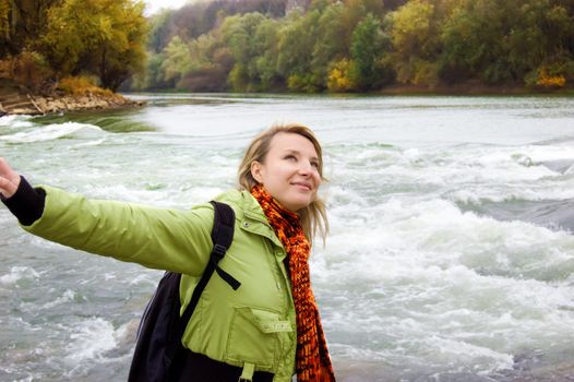 Young woman feeling free over late river autumn background