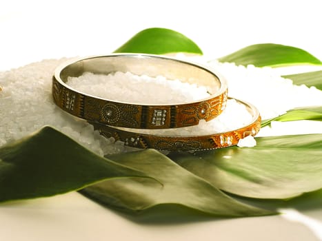 Two bracelets and bath salt on a green leaf