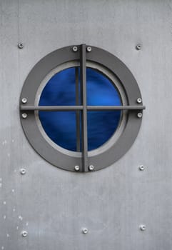 Silver metal door with porthole window with view on sea