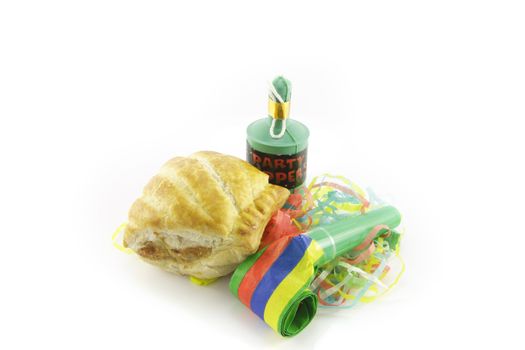 Small tasty sausage roll with party blower and party popper with streamers on a reflective white background