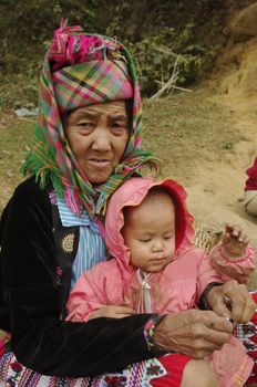 Hmong grandmother flowers and his little girl
 . The temperature has dropped for some time. It's cold in the mountains of northern Vietnam in February