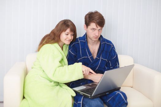 Couple sit on a sofa with the laptop