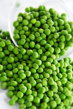 young fresh green spring peas scattered from glass bowl