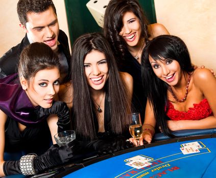 Group of young happy people in casino smiling behind black jack table