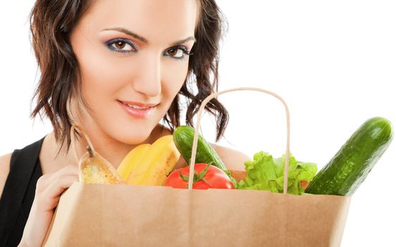 young female holding paper shopping bag full of groceries, looking at camera