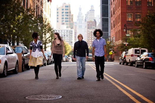 A group of young adults in an uban setting - walking on a road