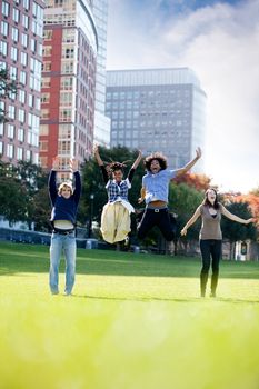 A group of happy people running towads the camera.  Sharp focus on rear three people, motion blur on front person.