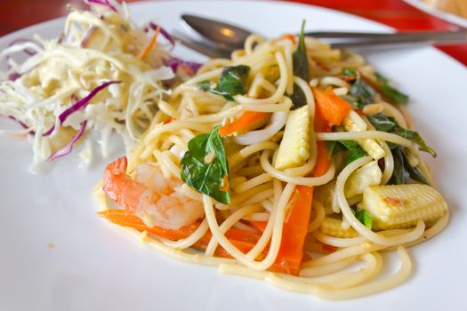 spaghetti whit shrimp and basil fried on a white dish